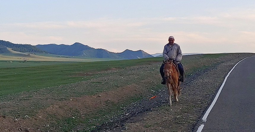 말을 타고 여유롭게 초원을 달리는 몽골인