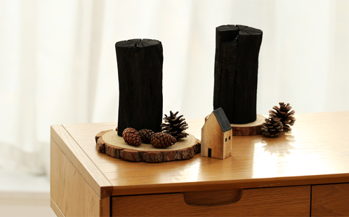 나무 접시 위에 숯 기둥과 솔방울이 있는 사진